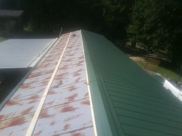 Old rusted panels beside newly installed green metal roofing — Wind Damage Roof Repair by Roofing Brothers in Hamlin